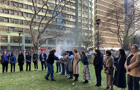 Row of people standing behind man as he carries out smoking ceremony