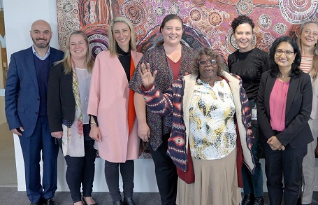 Row of people standing behind man as he carries out smoking ceremony