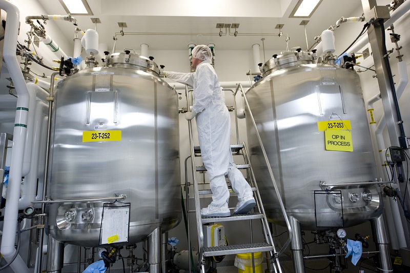 Man on a ladder looking at a bioreactor